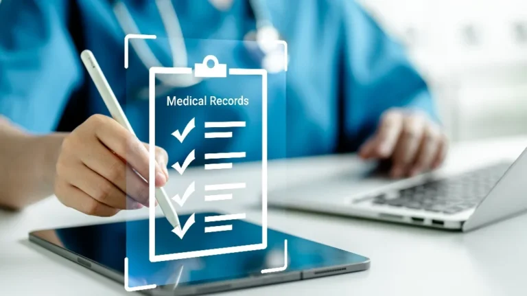 Person in medical scrubs using stylus on tablet with digital medical records display.